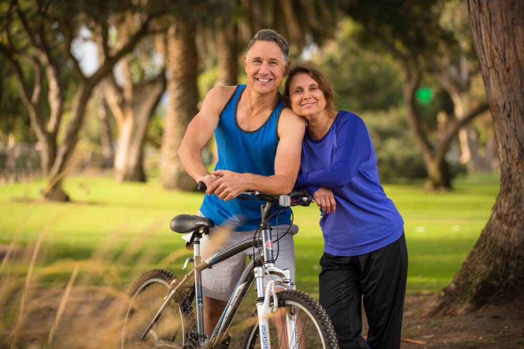 Happy couple with bike in park.