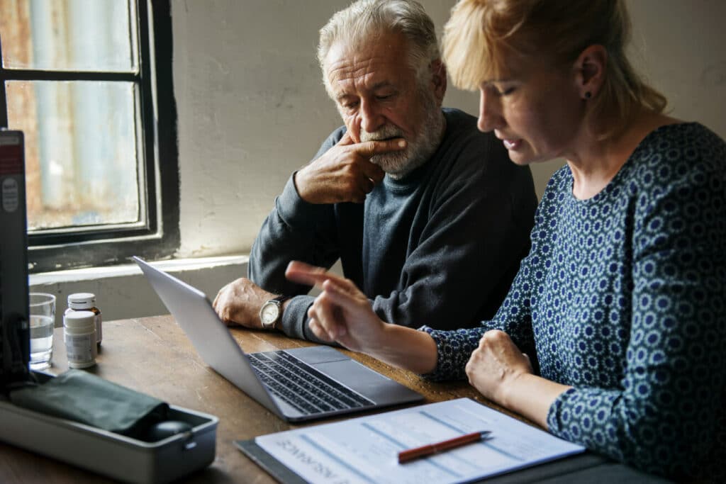 Senior couple reviewing finances on laptop at home.
