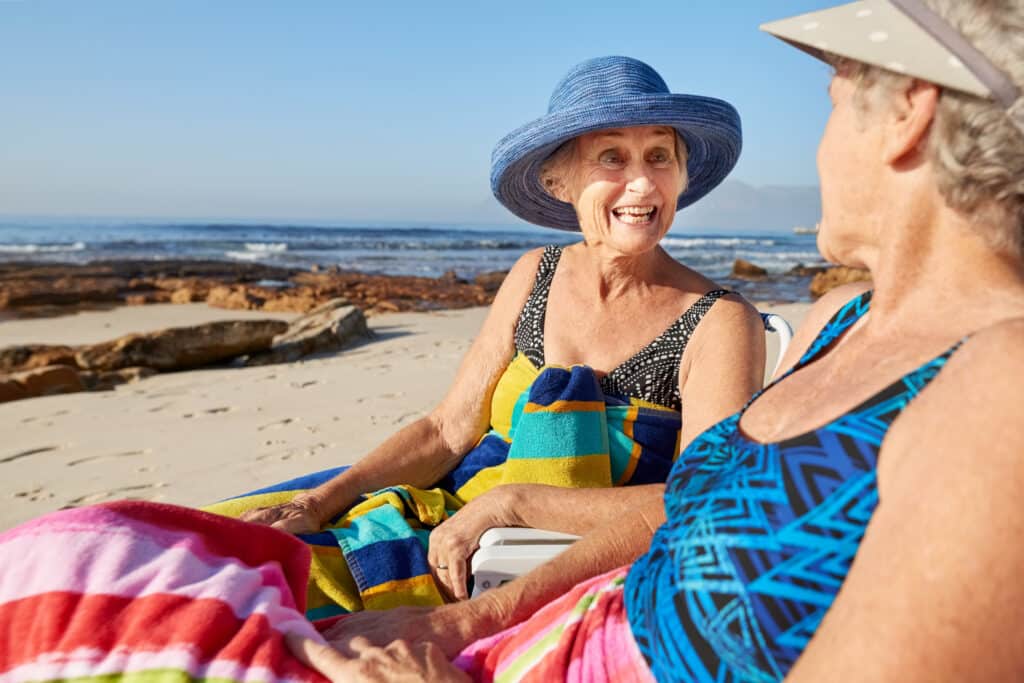 Senior women chatting on sunny beach.