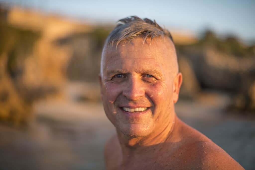 Smiling man on beach at sunset.