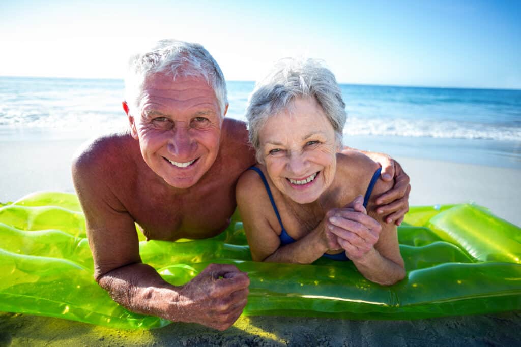 Senior couple smiling on beach float.