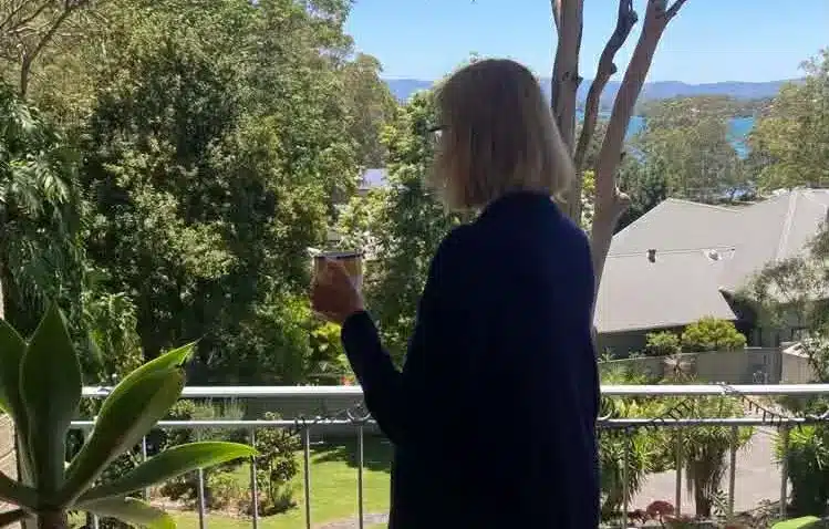 Image of lady looking out at greenery from household balcony